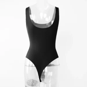 Transparent torso acrylic mannequin wearing a black sleeveless low cut bodysuit from the backside over a white wall.