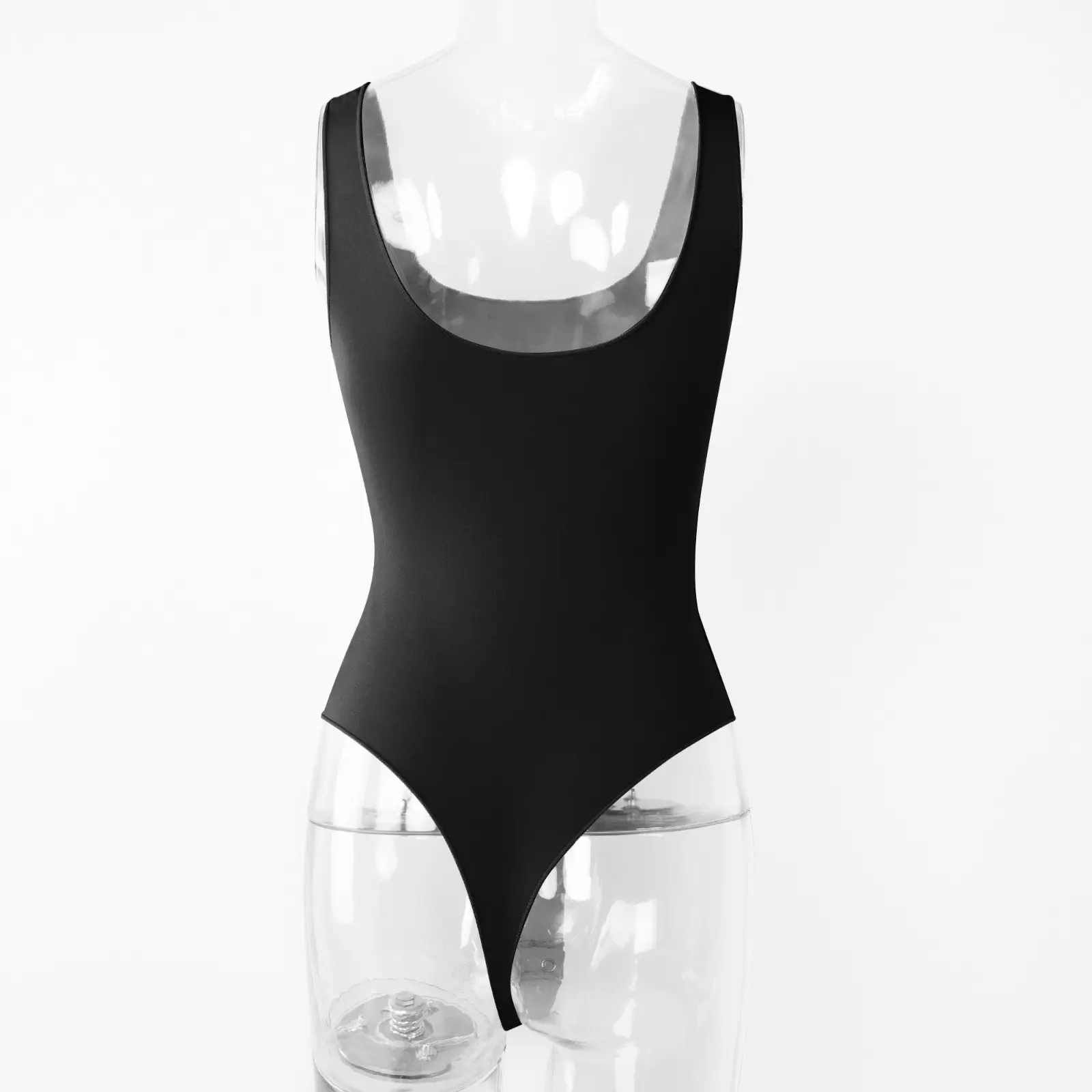 Transparent torso acrylic mannequin wearing a black sleeveless low cut bodysuit from the backside over a white wall.