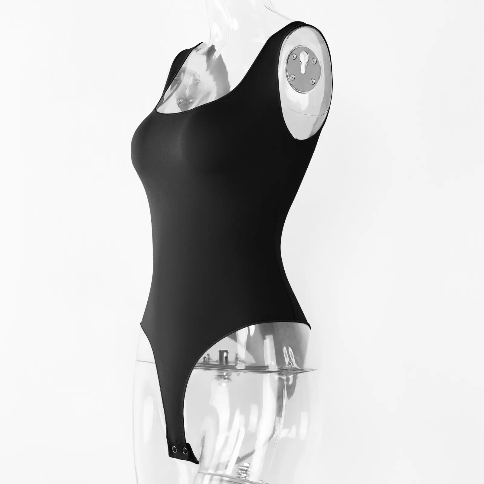 Torso transparent acrylic mannequin wearing a black sleeveless low cut bodysuit at an angle over a white wall.
