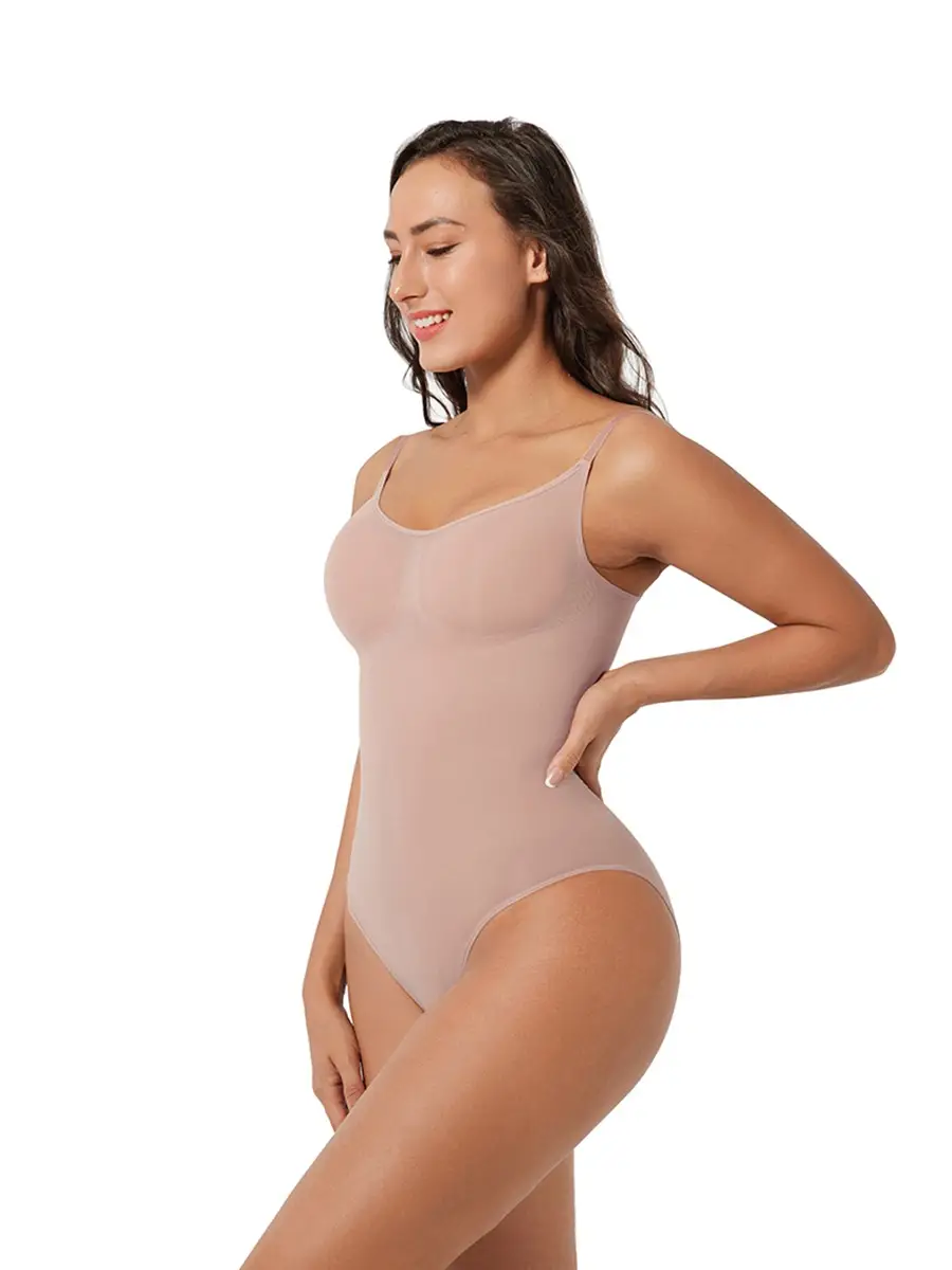 Hispanic woman posing with hand on hip wearing a beige brief bodysuit over a white background